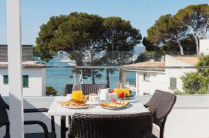 a table with food on a balcony with a view of the ocean at Hoposa Pollensamar Apartamentos in Port de Pollensa