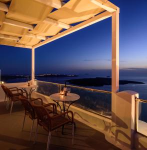una mesa y sillas en un balcón con vistas al océano en Vallas Apartments & Villas, en Firostefani
