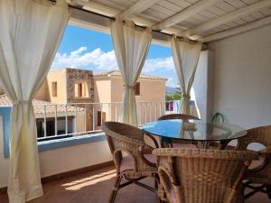 een balkon met een glazen tafel en stoelen en een raam bij Residenze S'ABBAIDA in Tanaunella
