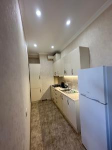 uma cozinha com armários brancos e um frigorífico branco em Apartment 45 em Tbilisi
