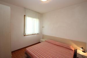 a white bedroom with a bed and a window at Raffaella in Bibione