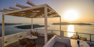 un balcón con mesas y sillas y el océano en Vallas Apartments & Villas, en Firostefani