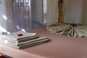 a pile of towels sitting on top of a bed at Shambala Madagascar: Beachfront Lodge And Adventures in Ambolobozo