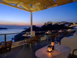 un restaurante con mesas y sillas y vistas al océano en Vallas Apartments & Villas, en Firostefani