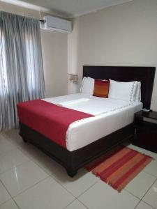 una camera da letto con un grande letto con una coperta rossa di The upperroom bed and breakfast a Francistown
