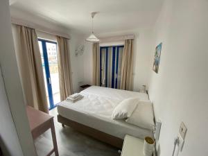 a white bedroom with a bed and a window at Kaloxenia in Kardamaina