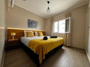 um quarto com uma cama com um cobertor amarelo em Vista Mar e Terra em Albufeira