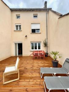 una terrazza in legno con tavolo e sedie su un edificio di Maison familiale rénovée au cœur de la Bastide ! a Castillonnès