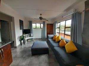 een woonkamer met een zwarte bank en gele kussens bij African Thistle in St Lucia