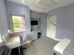 um quarto com uma cama, uma secretária e uma janela em Melbury Rooms & Studios em Exeter