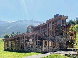 a large wooden building with mountains in the background at Les Balcons Platinium Val Cenis in Lanslevillard