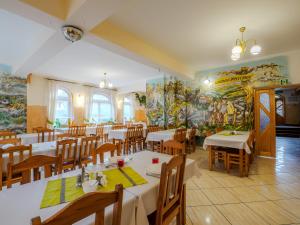 マウェ・チヘにあるOśrodek Wczasowy Pasternikのテーブルと椅子、壁画のあるレストラン