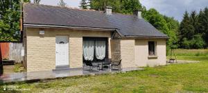 uma pequena casa de tijolos com duas cadeiras e uma porta branca em Ty case péi em Saint-Aignan