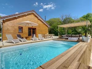 a pool with chairs and an umbrella next to a house at Domaine privé avec piscine et terrain de pétanque in Viéville