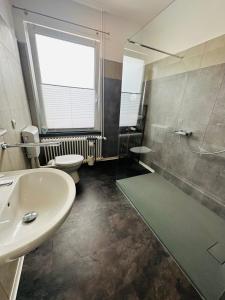 een badkamer met een wastafel, een douche en een toilet bij Pension Die Schlafstube in Neuharlingersiel
