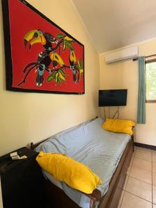 Un dormitorio con una cama con almohadas amarillas y una pintura en Tucan Studio Ocotal en Coco