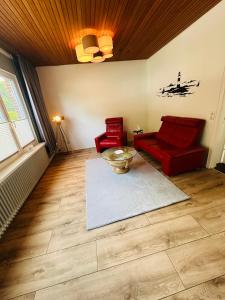 salon z 2 czerwonymi krzesłami i stołem w obiekcie Pension Die Schlafstube w mieście Neuharlingersiel