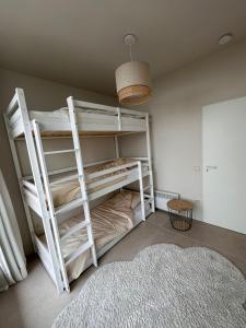 Zimmer mit Etagenbetten in einem Zimmer mit einem Teppich in der Unterkunft Appartement Sainte-Cécile in De Panne
