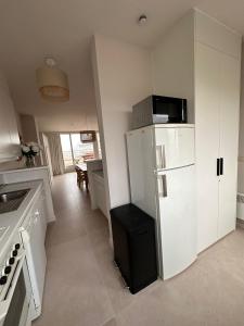 eine Küche mit einem weißen Kühlschrank und einem Tisch in der Unterkunft Appartement Sainte-Cécile in De Panne