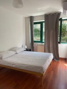 a bedroom with a bed with white sheets and windows at cuore di caserta in Caserta