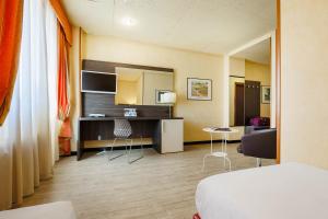 une chambre d'hôtel avec un lit, une table et des chaises dans l'établissement JR Hotels Bologna Amadeus, à Bologne