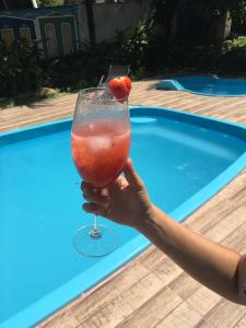 una persona sosteniendo una bebida con una fresa en ella en Pousada Villa Bella en Palmeiras