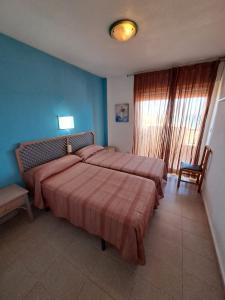 1 dormitorio con 1 cama grande y pared azul en Apartamentos Ágata V.v., en La Manga del Mar Menor