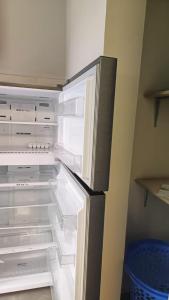an empty refrigerator with its door open in a kitchen at InDesign Makumbi Park Apartments near 67 airport hotel in Syokimau