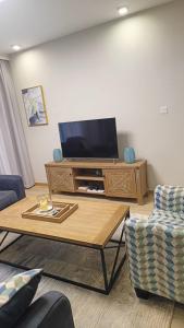 a living room with a tv and a coffee table at InDesign Makumbi Park Apartments near 67 airport hotel in Syokimau