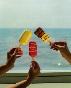 un gruppo di persone che tengono bastoncini di gelato davanti a una finestra di Blue sea view blue orbi a Batumi