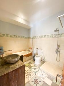 a bathroom with a tub and a toilet and a sink at Orchid Villa in Sanur
