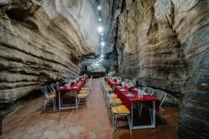 uma sala de jantar numa caverna com mesas e cadeiras em Victor Charlie Hostel em Ilha de Cát Bà