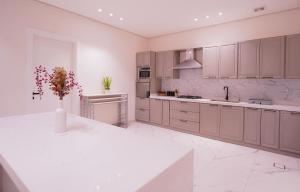 a kitchen with white cabinets and a vase with flowers at Pool villa فيلا من ثلاث غرف نوم in Butainiyāt