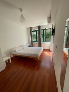 1 dormitorio con 1 cama, suelo de madera y ventanas en cuore di caserta, en Caserta