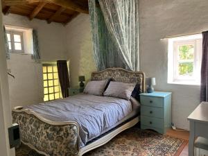 een slaapkamer met een bed, een dressoir en 2 ramen bij Maison des Roses in Saint-Savinien