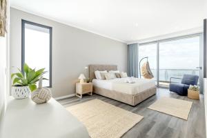 a white bedroom with a bed and a large window at Villa Serenity by Rentallido in Prazeres +37 photos
