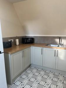a kitchen with white cabinets and a tile floor at Balmaha Lodges and Apartments in Balmaha