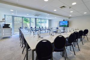 a conference room with tables and chairs and a flat screen tv at Quality Hotel La Marebaudière Vannes Centre in Vannes
