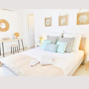 Naira Family Suites Mykonos في مدينة ميكونوس: غرفة نوم مع سرير أبيض كبير مع وسائد زرقاء