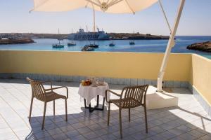 ein Tisch und zwei Stühle und ein Sonnenschirm auf dem Balkon in der Unterkunft Hotel Baia Turchese in Lampedusa
