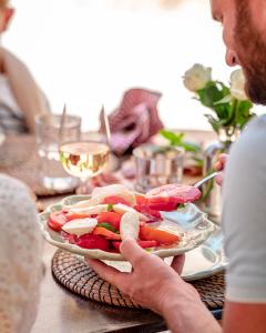 un hombre sosteniendo un plato de verduras en una mesa en Mas des Comtes de Provence en Tarascon