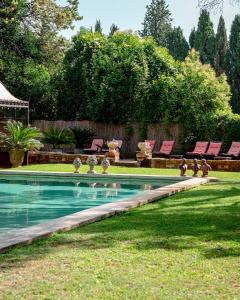 a swimming pool in a yard with pink lounge chairs at Mas des Comtes de Provence in Tarascon