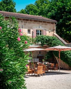 a patio with tables and umbrellas in front of a building at Mas des Comtes de Provence in Tarascon