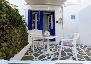 un tavolo bianco e sedie su una veranda con porta blu di Παραδοσιακή κατοικία στην αγορά a Paroikia