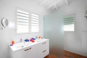 a white bathroom with a sink and two windows at Villa Flamboyant, heated swimming pool, sublime view of Anse Marcel, 4 bedrooms in Anse Marcel 