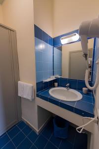 bagno piastrellato blu con lavandino e specchio di Hotel Baia Turchese a Lampedusa