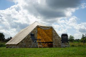 a tent with two chairs in a field at Tent-Ok Westerbeek in Westerbeek