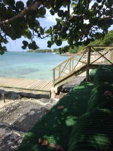 a wooden bench next to a beach with the ocean at Eco Hotel Las Palmeras in Isla Grande