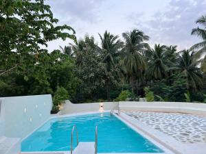 a swimming pool in a resort with palm trees at Wellnest Farm Retreat in Nagari