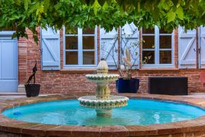 a fountain in front of a brick building at Suites romantiques spa privatif, piscine, jardin, massages proche de Toulouse in Verfeil